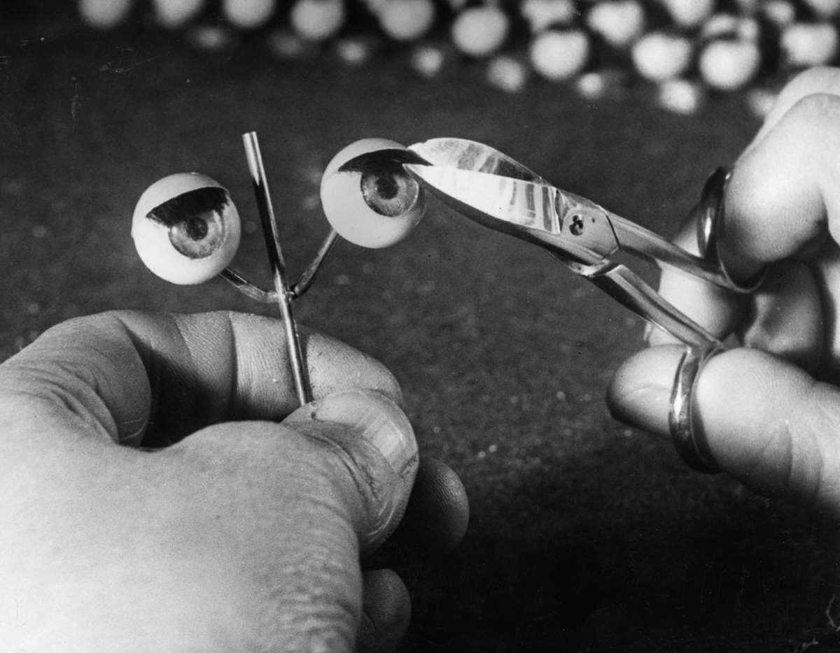 28th January 1949: A worker trims the eyelashes on a pair of doll's eyes at a factory in Totton, Southampton, which specialises in the manufacture of doll parts. (Photo by William Vanderson/Fox Photos/Getty Images)