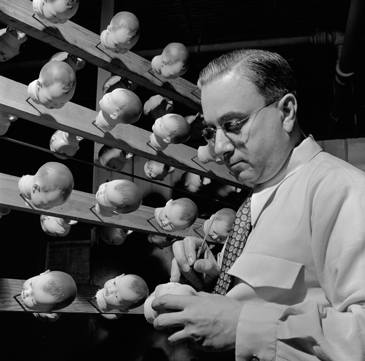 circa 1955: A factory worker painting the heads of plastic dolls in preparation for the Christmas trade. (Photo by Evans/Three Lions/Getty Images)