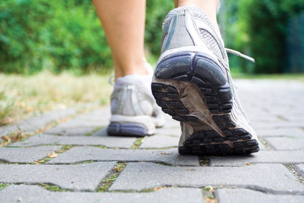 Woman walking on sidewalk, sport shoes close-up