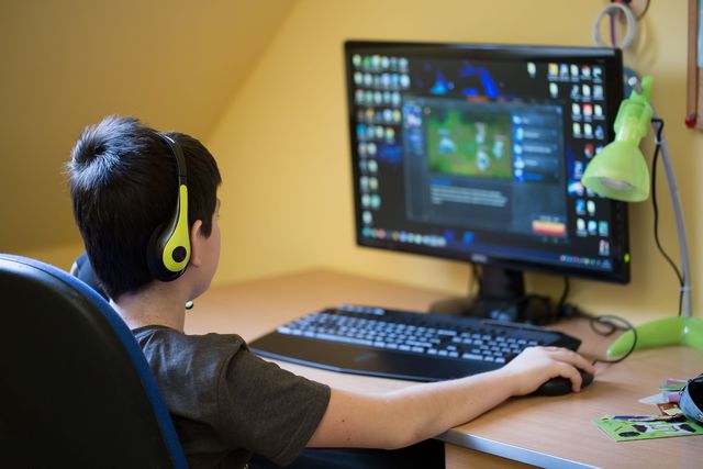 Teenager using computer at home with headphones, play game in his child room