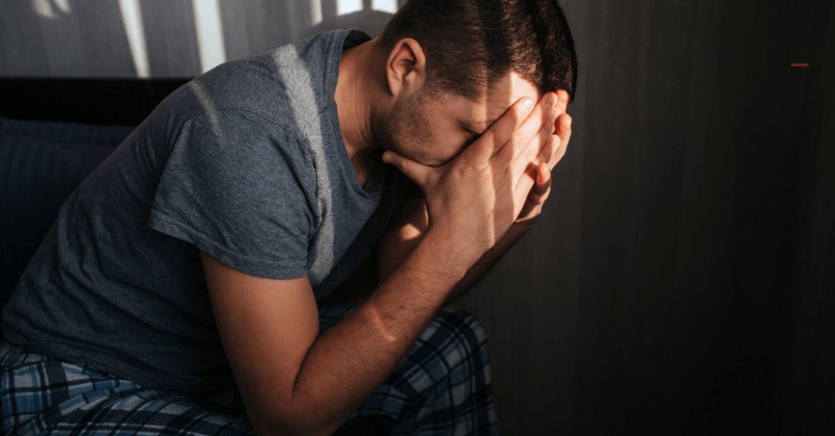 smutny mężczyzna ukrywający twarz w dłoniach