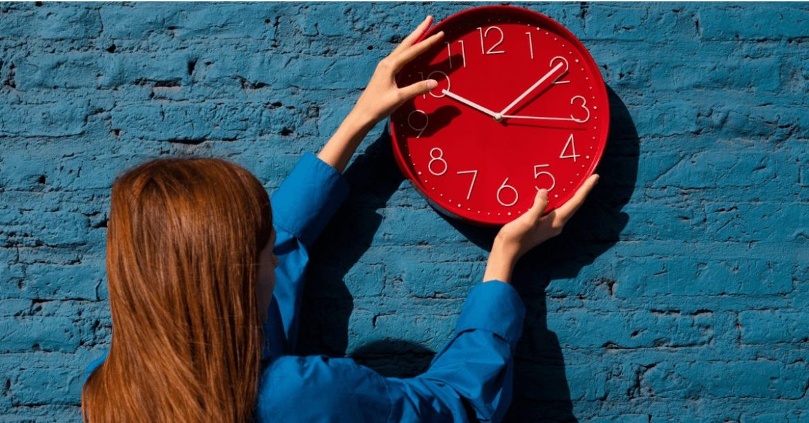 dziewczyna wieszająca zegar na ścianie