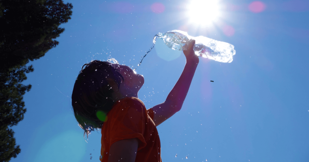 dziecko pijące wodę z butelki na tle słońca