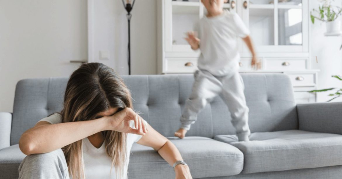 zmęczona mama i synek skaczący na kanapie